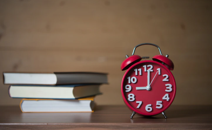 The red clock next to textbooks to indicate exam time