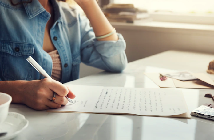 A woman practicing writing a letter for the IELTS test