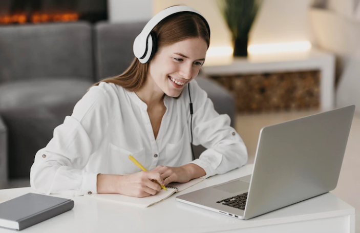 A girl wearing headphones is practicing the IELTS listening test