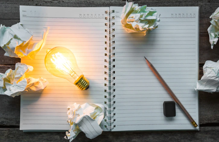 A notebook and pencil with crumpled papers