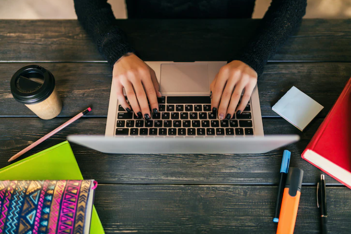 The laptop is shown from above, and a girl is typing