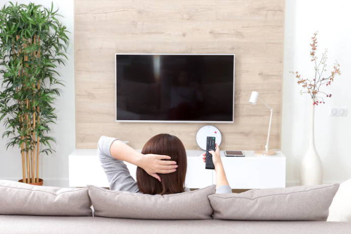 The girl that has control and sitting in front of the TV