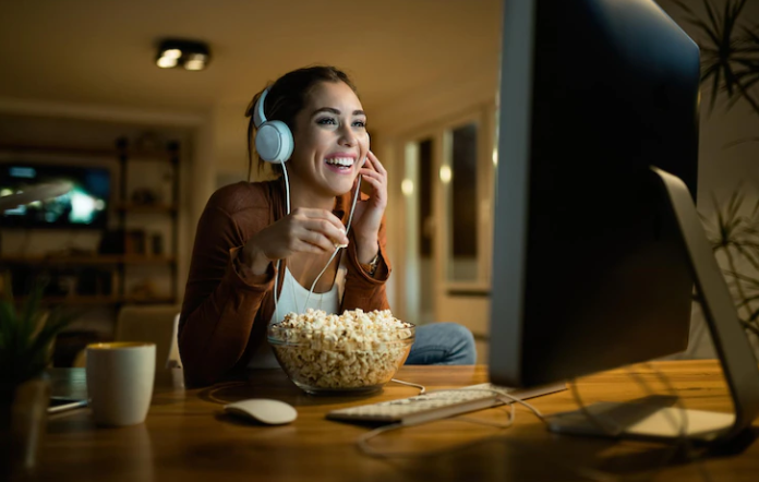 A girl who is watching a movie with headphones and laughing