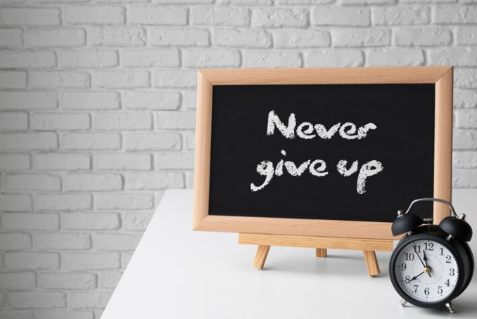 A board on which the sentence "never give up" is written