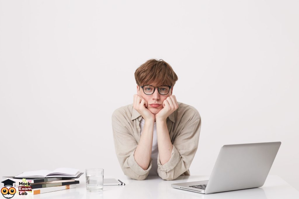 A tired student with glasses behind his desk