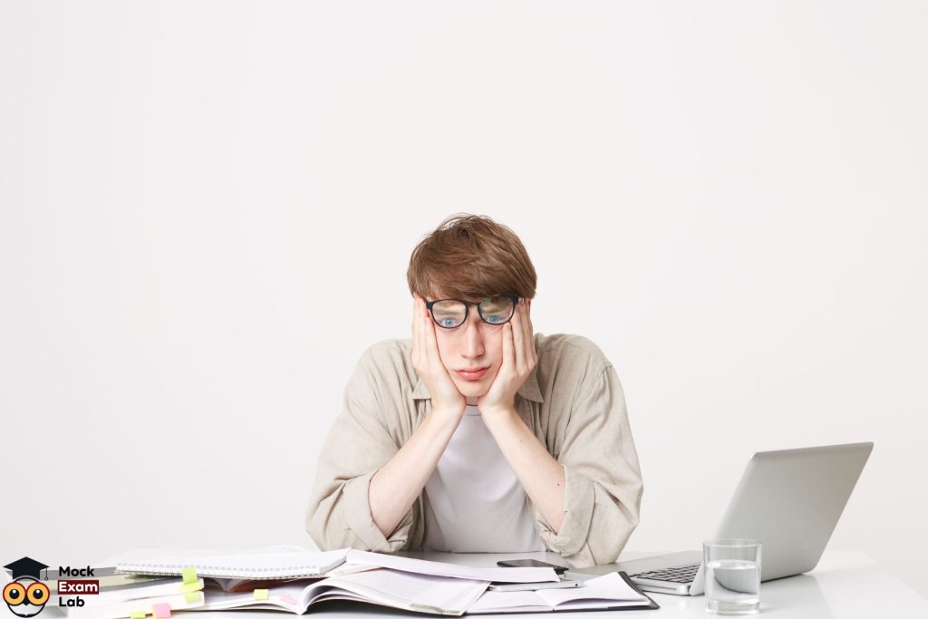 A tired student with speaking anxiety is sitting behind his desk.